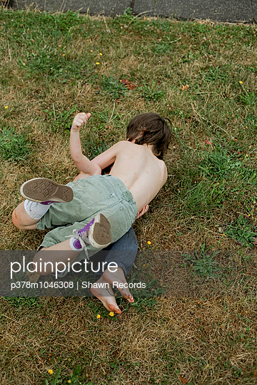 Two shirtless boys wrestling in the grass. Portland, Oregon, U.S.A