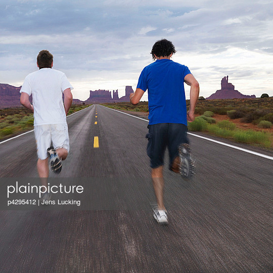 Two men jogging on road in desert