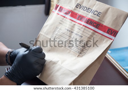 forensic \'s hand in black glove writing on evidence bag and seal by red tape in crime scene investigation