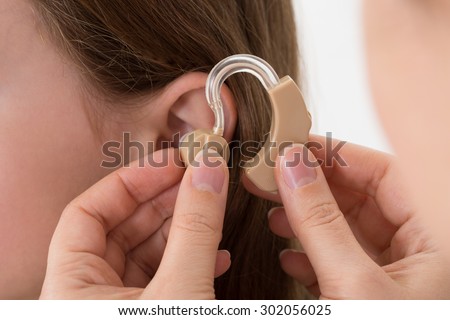 Close-up Of Doctor Inserting Hearing Aid In The Ear Of A Girl