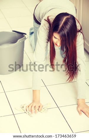 Young woman cleaning flor on her knees