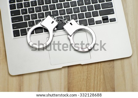 Handcuffs on notebook, symbolizing cyber crime