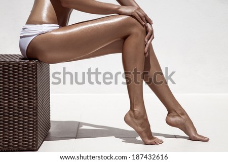 Beautiful woman tan legs. Against white wall.