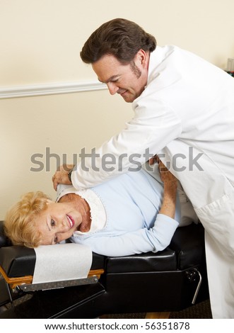 Gentle chiropractor adjusting happy senior patient in his office.