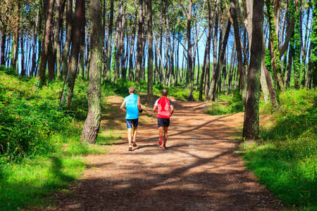 LIENCRES DUNES, SPAIN - AUGUST, 21: Two men jogging in a path between the trees on August 21, 2016