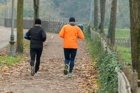 Two men jogging in park in autumn. Health and fitness