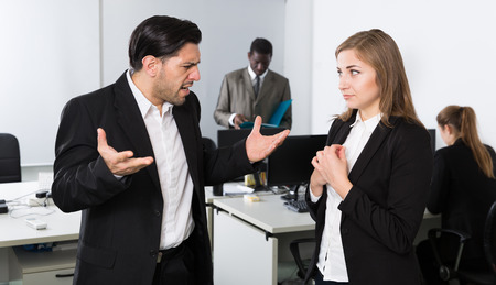 Angry man boss pointinting to misses in work to female manager working in office