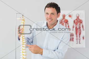 Handsome smiling doctor pointing at skeleton model