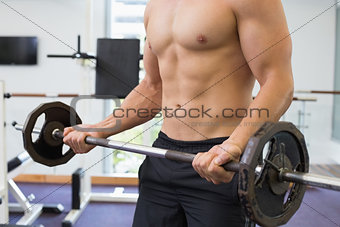 Shirtless bodybuilder lifting heavy barbell weight