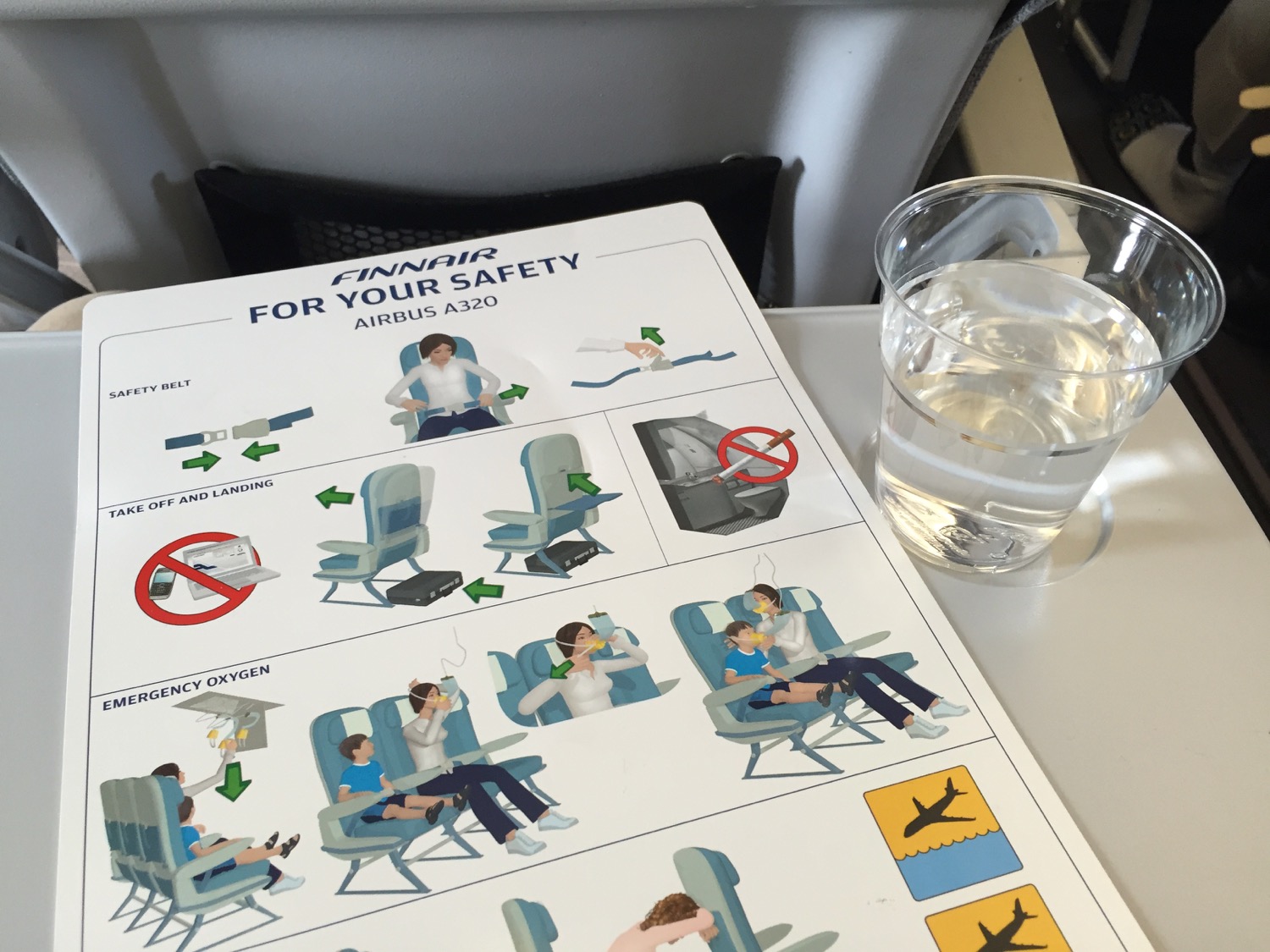 a glass of water next to a sign on a plane