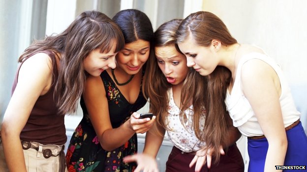 Girls corwded around a mobile phone