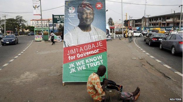 A shoe-mender works near a poster campaigning for frontline contender and Lagos governorship candidate for the People's Democratic Party (PDP)