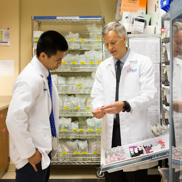 Two men in lab coats talk over samples.