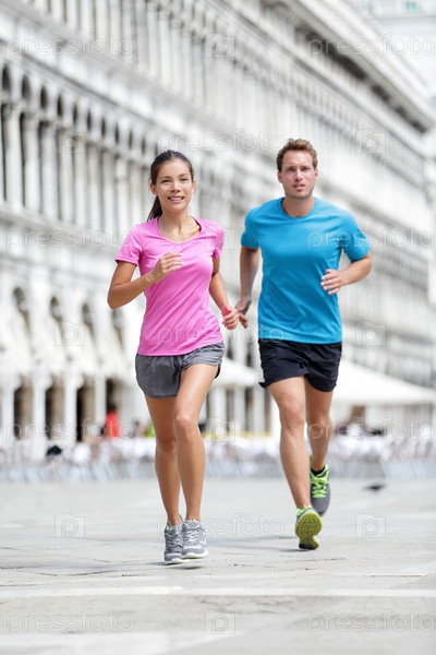 Running runner couple jogging in Venice. Two runners, Asian woman and Caucasian man training on travel vacation as tourists on Piazza San Marco Square, Venice, Italy, Europe.