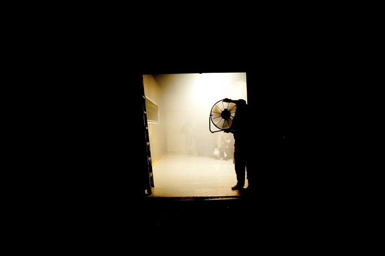 A member of the audience holds a fan to air out the competition venue. The room becomes so cloudy with vapor during contests that it has to be fanned out between rounds.