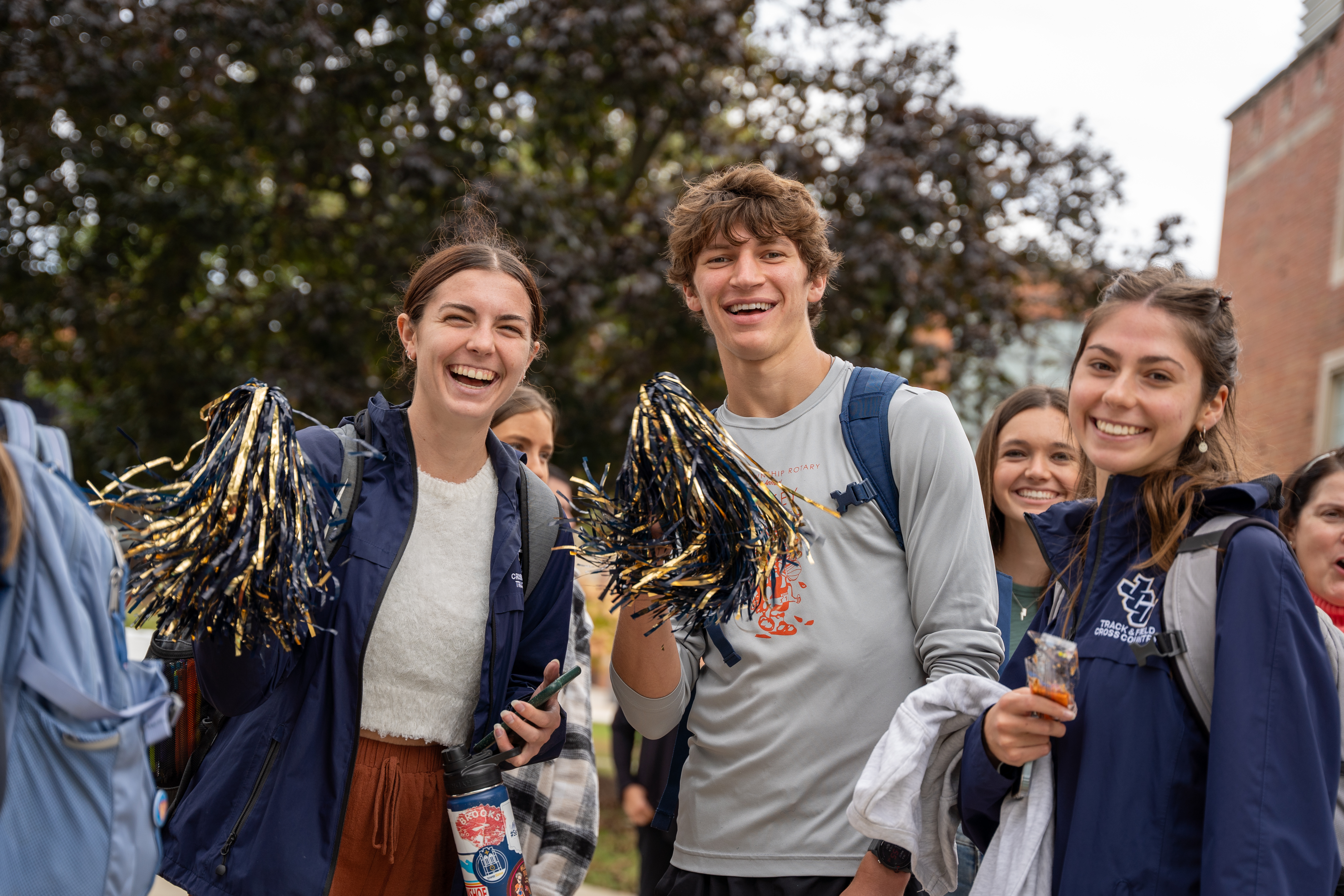 three students with jcu themed pom poms