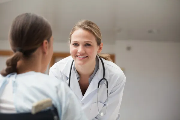 Smiling doctor looking at a patient on a wheelchair