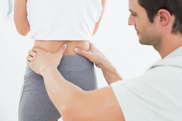 Mid section of a physiotherapist examining woman\'s back