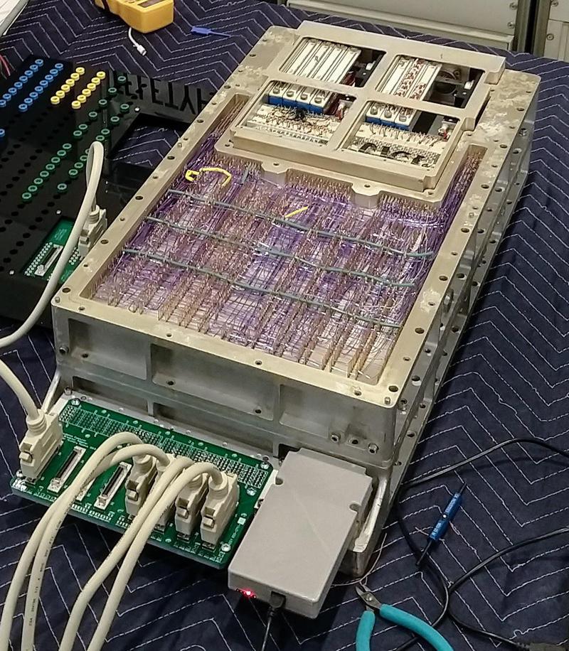 The Apollo Guidance Computer powered up. The cover is off, showing the computer's purple wire-wrap wiring of the backplane. We built the interfaces that are plugged into the front of the computer. At the back, vintage core rope simulator boxes are visible in the core rope slots.