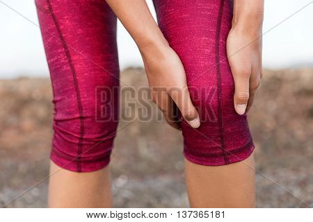 Runner woman gripping painful hurt knee pain. Athlete woman running outside with body injury. Closeu