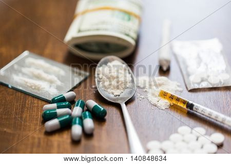 drug use, crime, addiction and substance abuse concept - close up of drugs with  money, spoon and sy