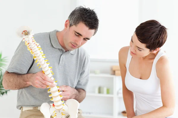 Chiropractor and patient looking at a model of a spine