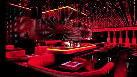 a dimly lit bar with red lighting and leather seating around the bar ...