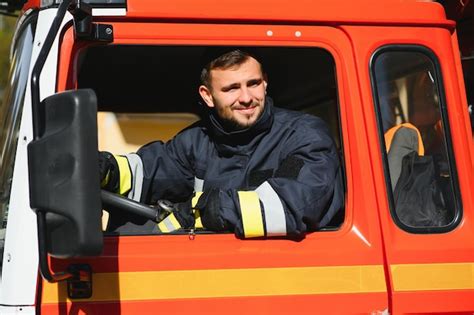 Premium Photo | Portrait of happy young fireman driving firetruck at ...