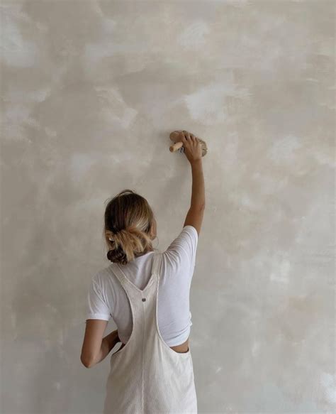 a woman is painting the wall with white paint and she has her hands up ...