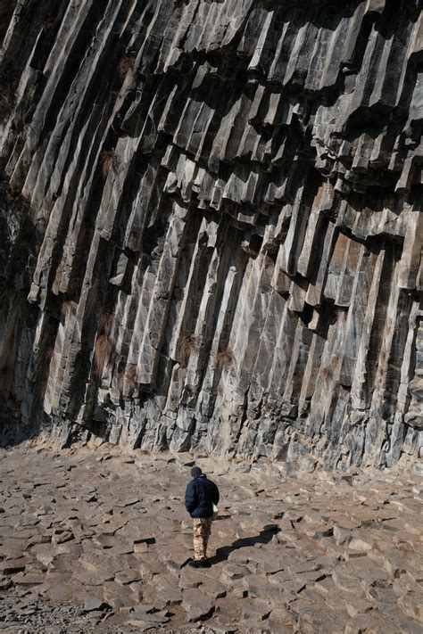 A person standing in front of a large rock formation photo – Free ...