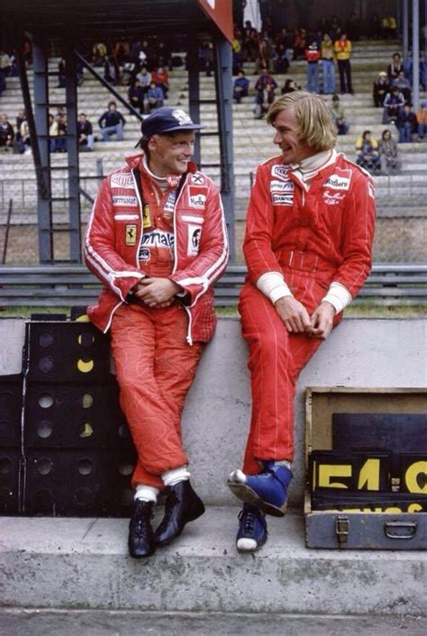 two men sitting next to each other on the side of a race track wearing ...