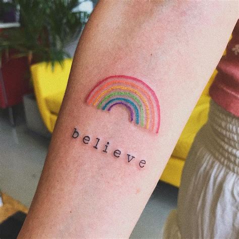 a person with a rainbow tattoo on their arm that says believe and the ...