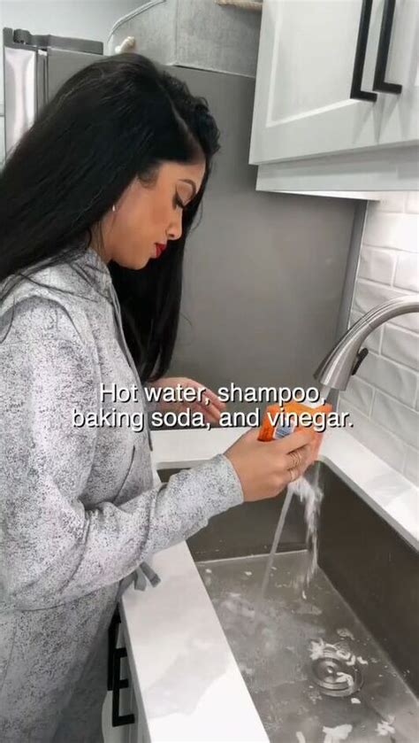 a woman is washing her hands in the kitchen sink while holding an ...