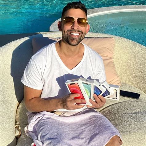 a man sitting on top of a white couch next to a swimming pool holding cards