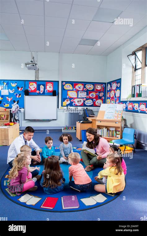 Group of nursery children sitting on the floor in their classroom with ...