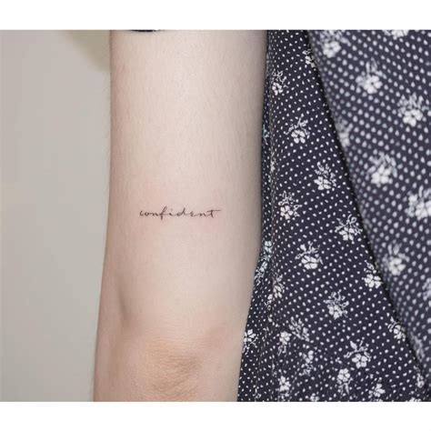 Tattoo of the word "confident" handwritten on the