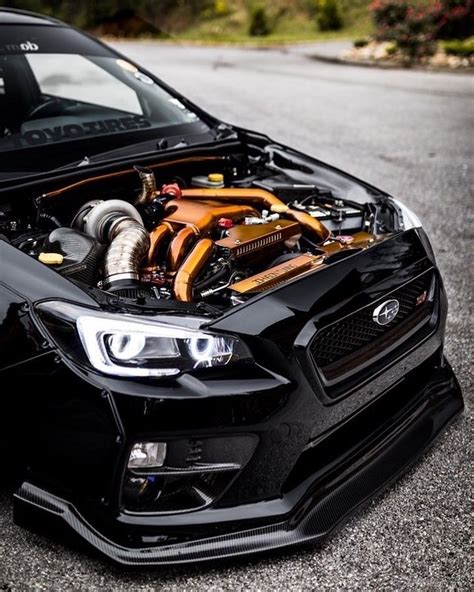 the front end of a black subarunt car with its hood up and engine on