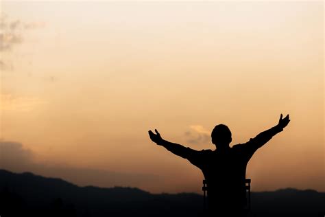 Silhouette of a man lift hands up and prayer and worship God at sunset ...