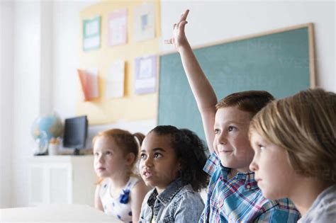 Student raising hand in classroom stock photo