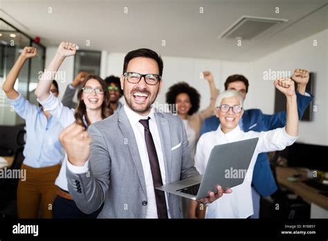 Happy business people celebrating success at company Stock Photo - Alamy