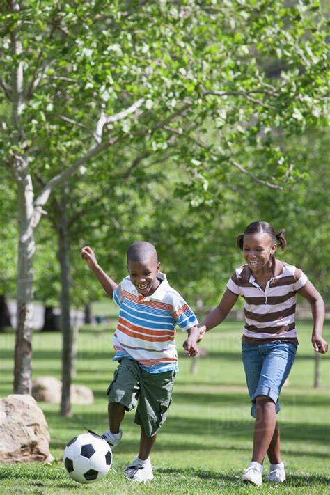 African American children playing soccer in park - Stock Photo - Dissolve