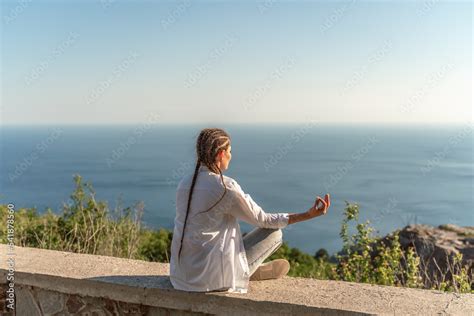 Profile of a woman doing yoga in the top of a cliff in the mountain ...