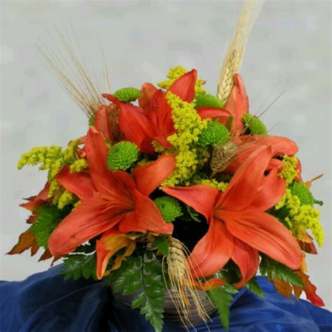 an arrangement of flowers in a basket on a blue cloth