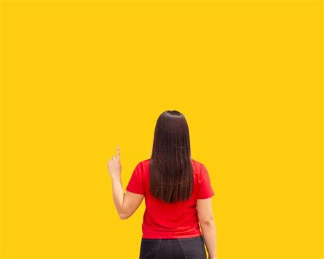 Premium Photo | Woman with arm up pointing on yellow background