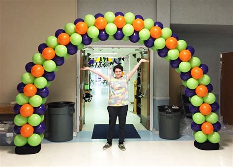 a woman standing in front of an arch made out of balloons