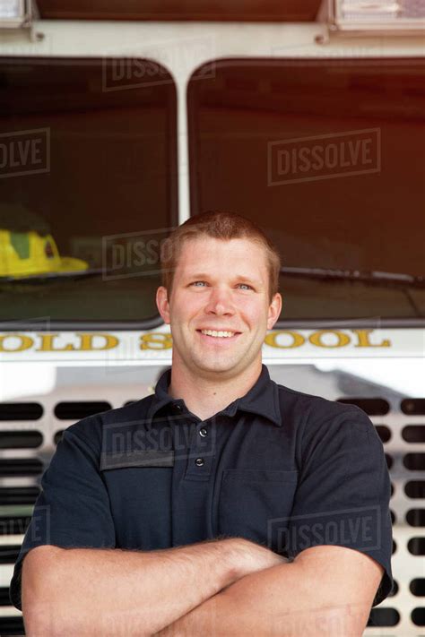 Portrait of Fireman standing in front of firetruck with arms crossed ...