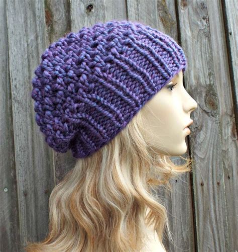 a mannequin head wearing a purple knitted hat on top of a wooden fence