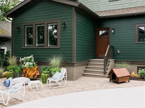 a green house with white lawn chairs in front