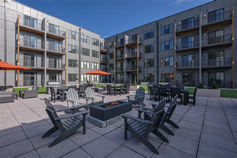 an outdoor patio with chairs, tables and fire pit in front of apartment ...