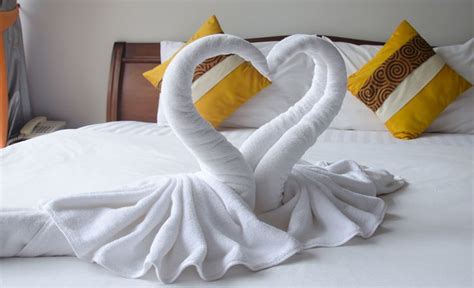 White towels folded into a swan shape on a bed. | How to fold towels ...